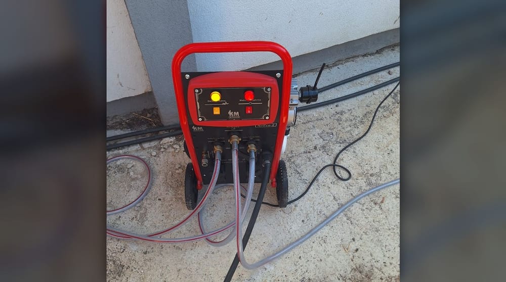 Tesisatın gidiş ve dönüş hattına hortumlarla bağlanmış kırmızı Kammak AirPro-2 petek temizleme makinesi