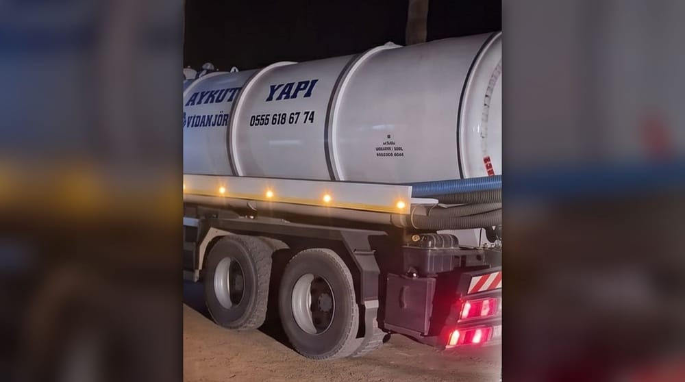 Aykut Yapı yazılı beyaz tankerli vidanjör aracı; tankın üstünde telefon numarası, yanında emme hortumları